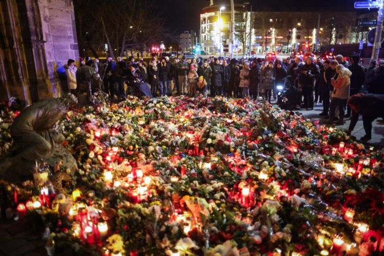 People lay flowers at a makeshift memorial near the site of a car-ramming attack on a Christmas market in Magdeburg, eastern Germany, on December 21, 2024. The death toll in the attack on December 20, rose to 5 on December 21, 2024, with over 200 injured, according to the head of the regional government, Reiner Haseloff. (Photo by Ronny HARTMANN / AFP)